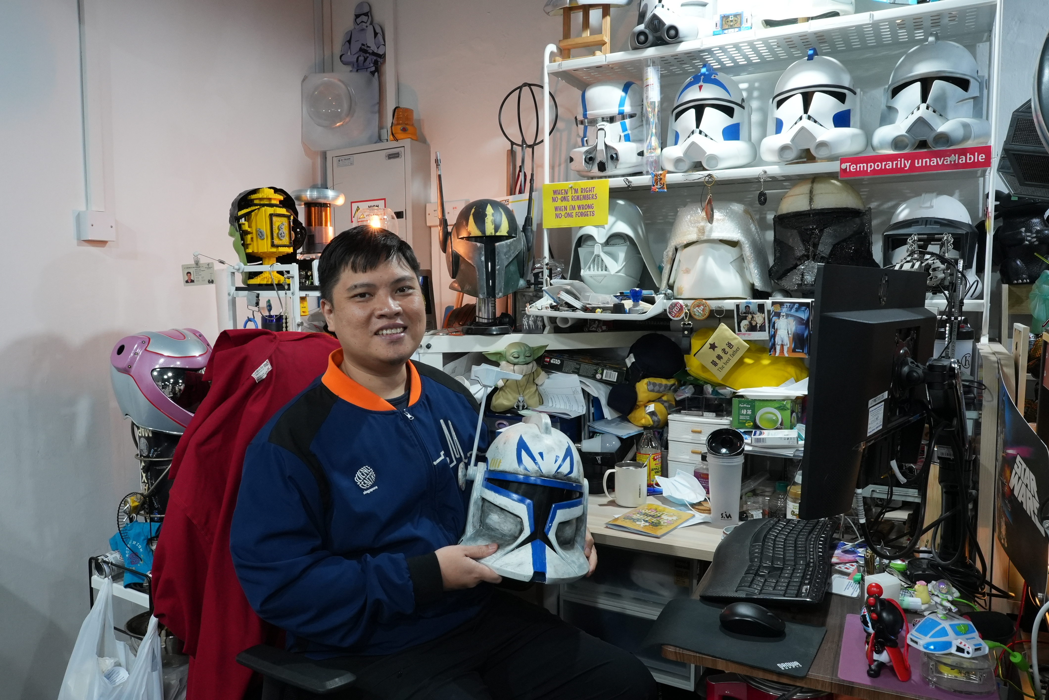 James Lim showcasing a Captain Rex helmet at his desk.