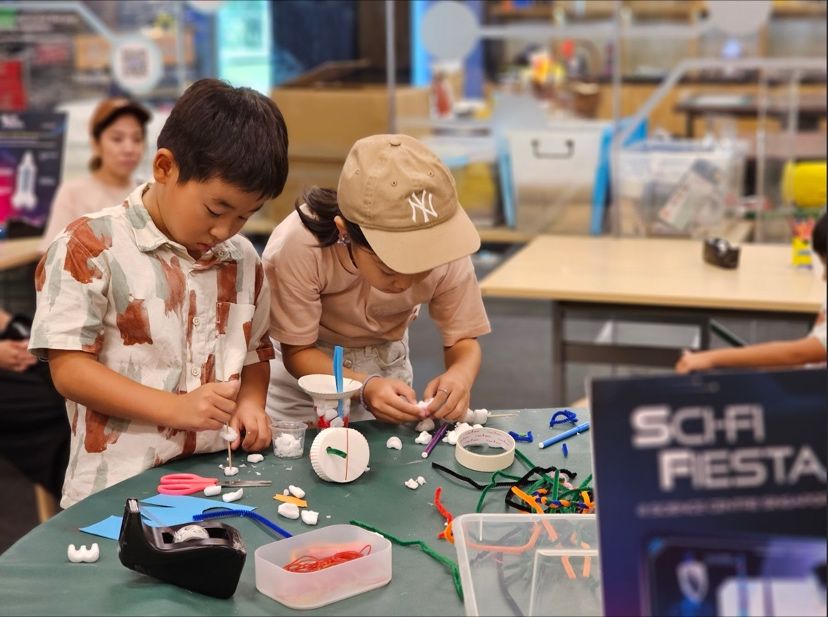 Kids building rocket ships out of everyday craft materials at Tinkering Studio during Sci-Fi Fiesta.